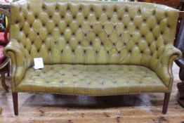 Green buttoned leather and studded wing back settee.