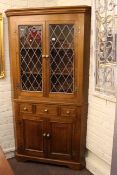 Oak standing corner cabinet having two leaded glazed doors above three drawers with two cupboard