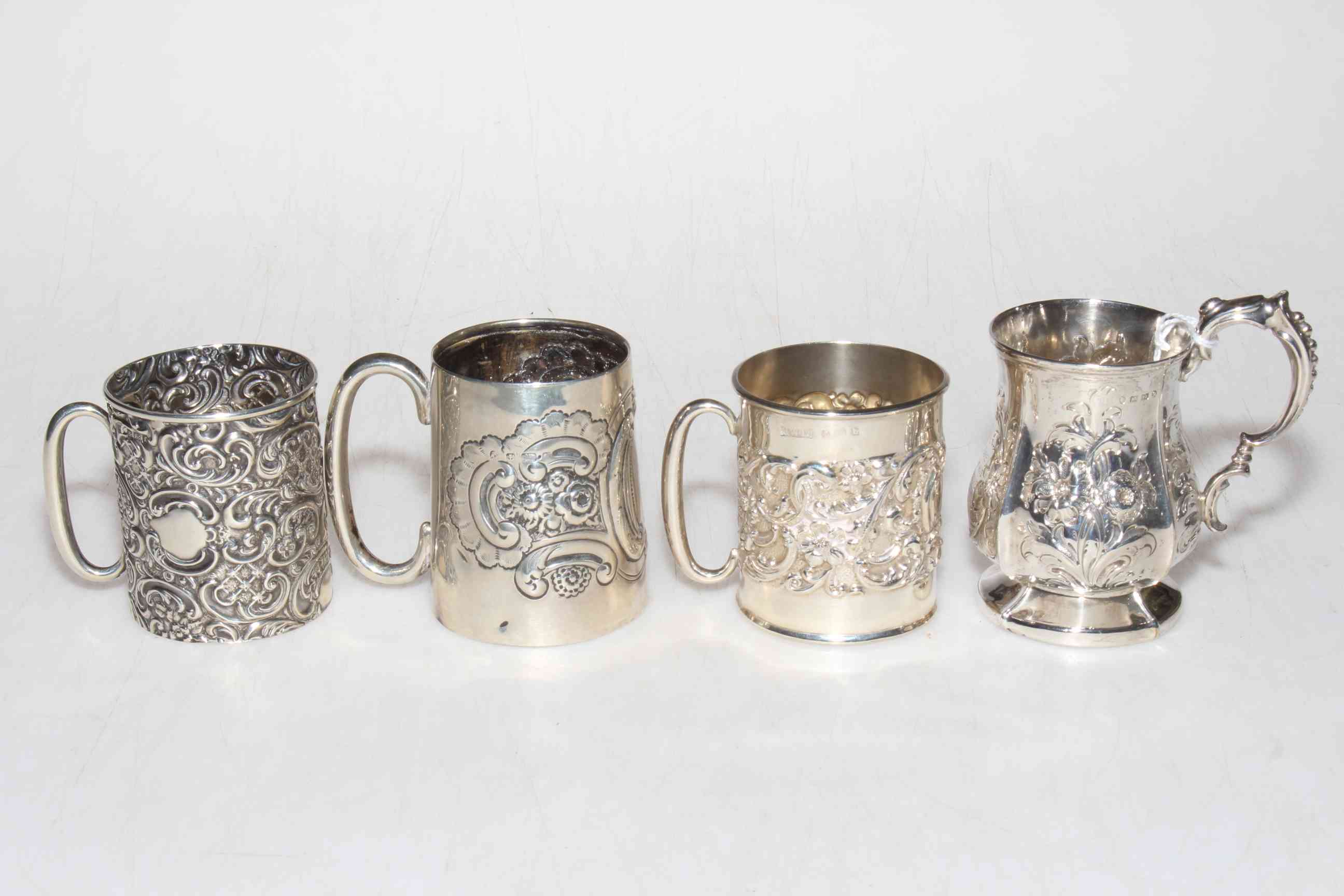 Victorian and three Edwardian small silver tankards, all with embossed floral decoration.