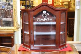 Arched top glazed door wall cabinet with canted corners marked Omega Watches, 52.5cm by 55.