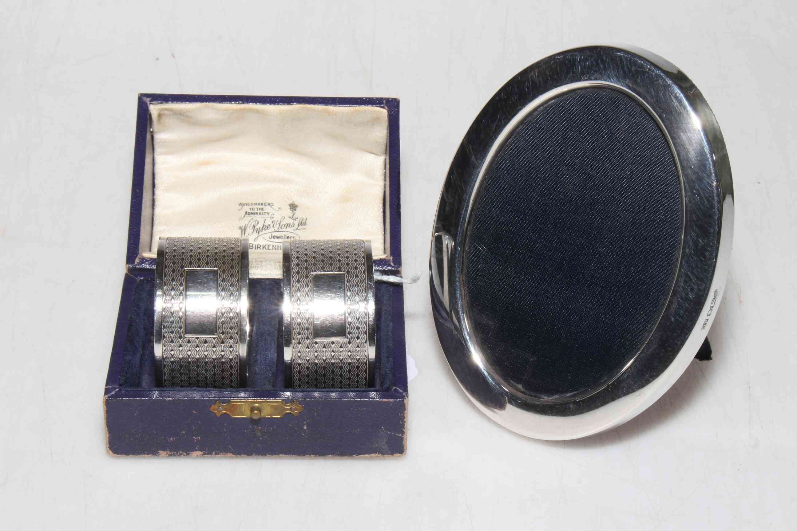 Small oval silver photograph frame and pair of cased silver napkin rings.