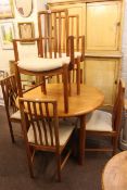 Circular teak extending dining table and six chairs including pair carvers.