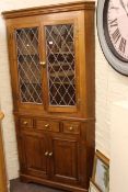 Oak standing corner cabinet having two leaded glazed doors above three drawers with two cupboard