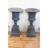 Pair cast Campana style garden urns on stepped bases, 87cm by 47cm diameter.