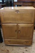 Ercol Windsor bureau, the fall front above two doors with a drawer below, 110cm by 82cm by 43cm.