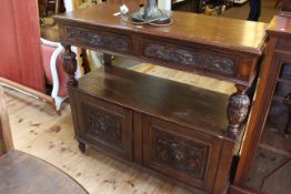 Carved oak buffet having two lion mask drawers above an open compartment with two cupboard doors