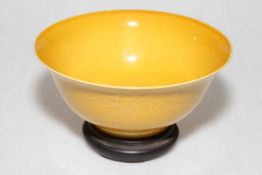 Chinese yellow glazed dragon bowl with hardwood stand, 15cm diameter.