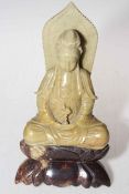 Malachite stone figure of seated Goddess on stand.