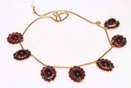 Gold chain cabachon garnet necklace, the chain hung with seven garnet cluster pendants.