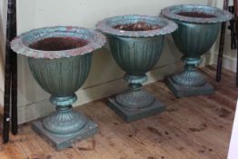 Set of three cast pedestal garden urns on square bases, 51cm by 45cm diameter.
