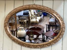 Ornate oval gilt framed bevelled wall mirror, 62cm by 87cm including frame.