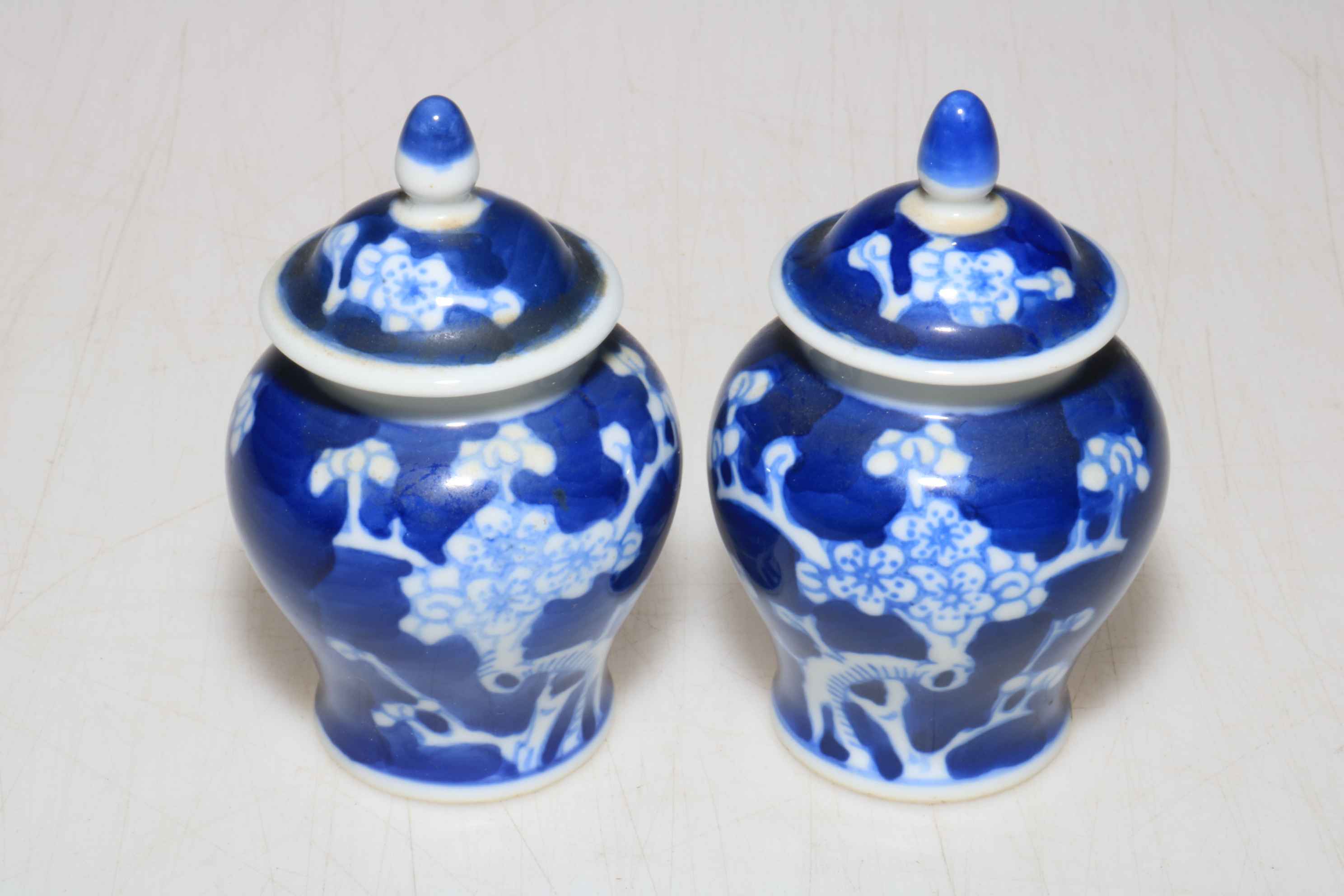 Pair of small ovoid lidded Chinese prunus vases, 9cm.