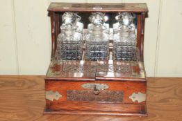 Carved oak and silver plate mounted three bottle tantalus with key.