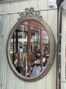 Oval wall mirror, 95cm by 70cm approximately.