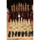 Two chess sets with boards, one being onyx and the other resin pieces with a carved wood board.