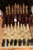 Two chess sets with boards, one being onyx and the other resin pieces with a carved wood board.