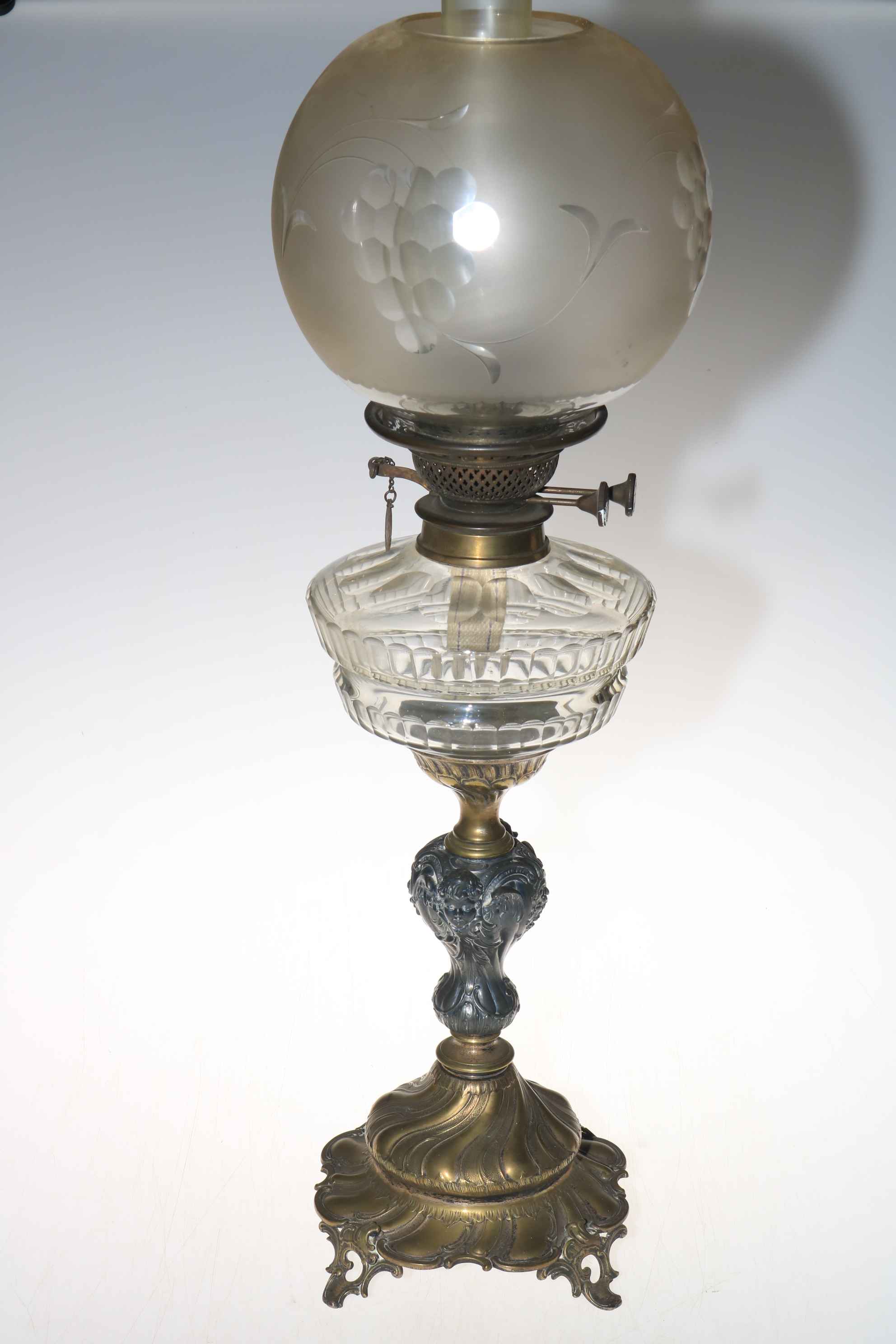Victorian oil lamp depicting ornate cherub column and etched grape shade.