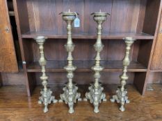Two pairs of brass candlesticks, 64cm and 48cm high.