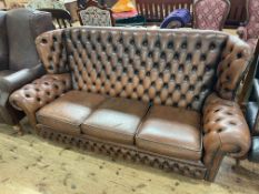 Brown deep buttoned leather three seater wing back Chesterfield settee.