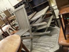 Weathered teak octagonal garden table and five folding chairs.