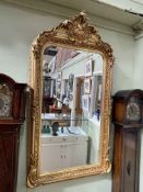 Rectangular gilt framed bevelled wall mirror with swag and floral crest, 156cm by 85cm.