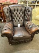 Brown deep buttoned leather Chesterfield wing back armchair.