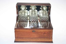 Edwardian inlaid mahogany three bottle tantalus with front compartment above secret drawer.