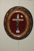 Oval gilt framed crucifix behind domed glass, 32cm by 27cm.