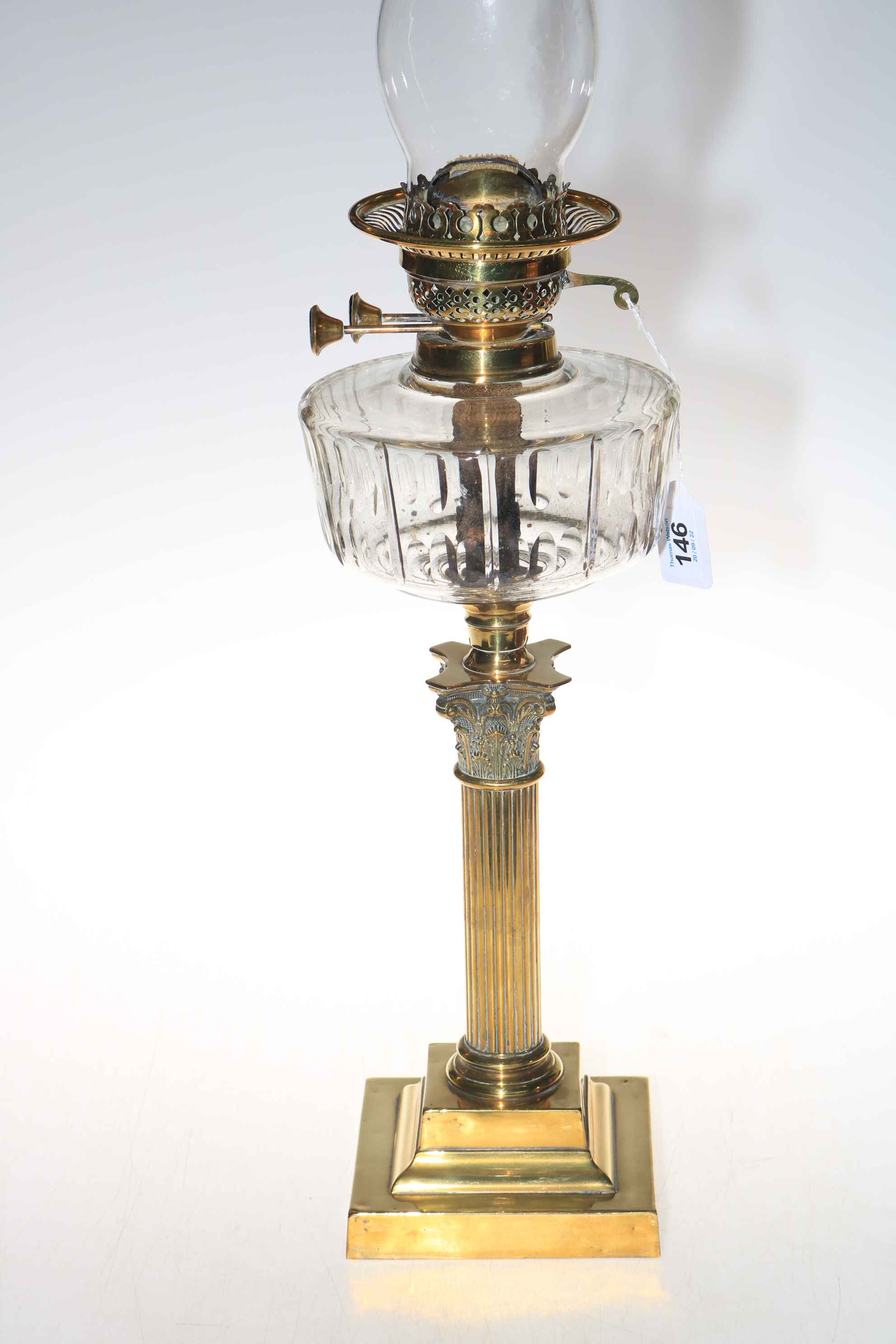 Brass Corinthian column oil lamp with clear glass reservoir, 71cm.