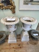 Pair cast Campana style twin handled garden urns on tapering plinth bases, 85cm by 45cm diameter.