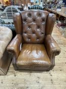 Tan leather button backed and studded wing armchair.