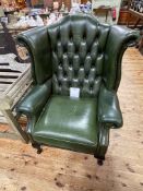 Green buttoned backed leather and studded wing armchair.