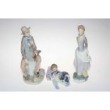 Three Lladro figurines, Male Violinist, Lady Holding Book and Boy with Dogs, two with boxes.
