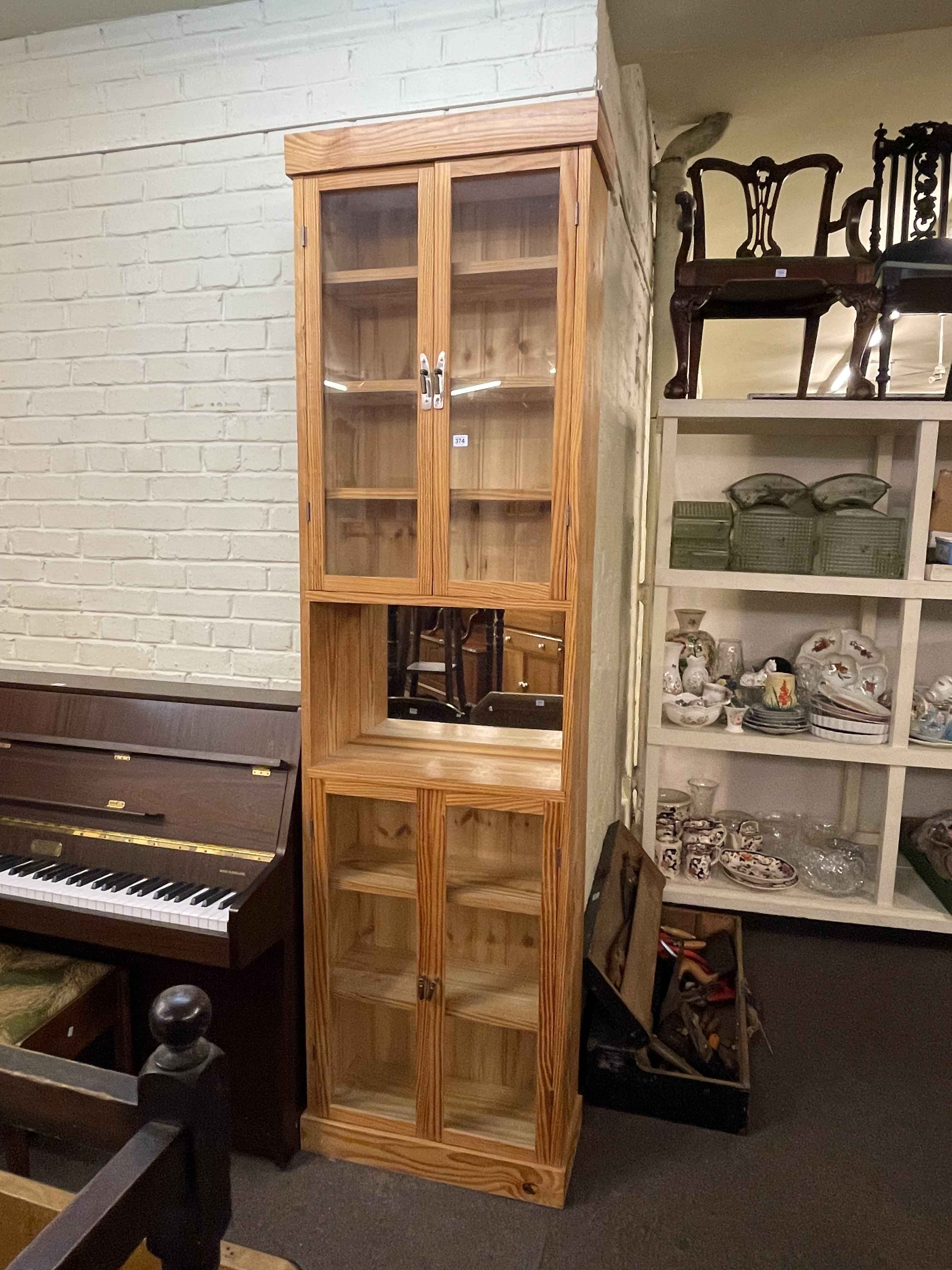 Tall pine glazed four door cabinet, 232cm by 65cm by 27cm.