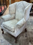 Wing armchair on ball and claw legs in light classical fabric.