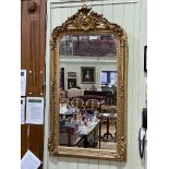 Rectangular gilt framed bevelled wall mirror with foliate crest, 155.5cm by 83cm.