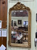 Rectangular gilt framed bevelled wall mirror with foliate crest, 155.5cm by 83cm.