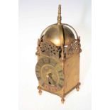 Ornate brass lantern clock with black Roman numeral dial.