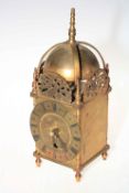 Ornate brass lantern clock with black Roman numeral dial.