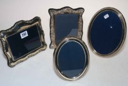 Four silver easel photograph frames, two oval and two ornate shaped.