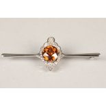 Unmarked white gold diamond and topaz bar brooch, a central circular cognac coloured topaz