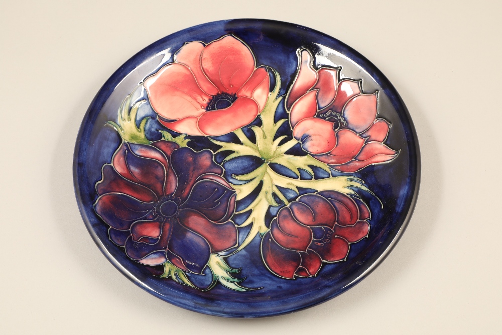 Moorcroft pottery wall plate, dark blue ground, decorated with anemone pattern Diameter 26.5cm