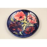 Moorcroft pottery wall plate, dark blue ground, decorated with anemone pattern Diameter 26.5cm