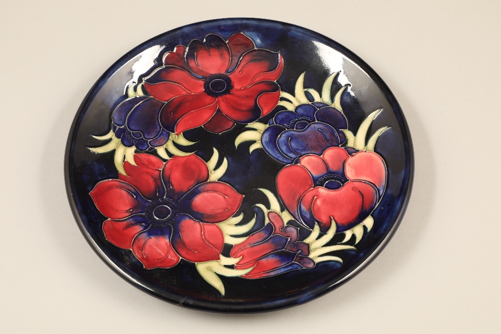 Moorcroft pottery plate, dark blue ground, decorated with anemone pattern Diameter 26cm