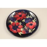 Moorcroft pottery plate, dark blue ground, decorated with anemone pattern Diameter 26cm