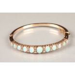 Gold stiff bangle set with eleven graduated oval opals, interspersed between small diamonds (28),