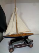 A wooden model of a yacht together with a contemporary tin plate vintage racing car