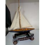 A wooden model of a yacht together with a contemporary tin plate vintage racing car