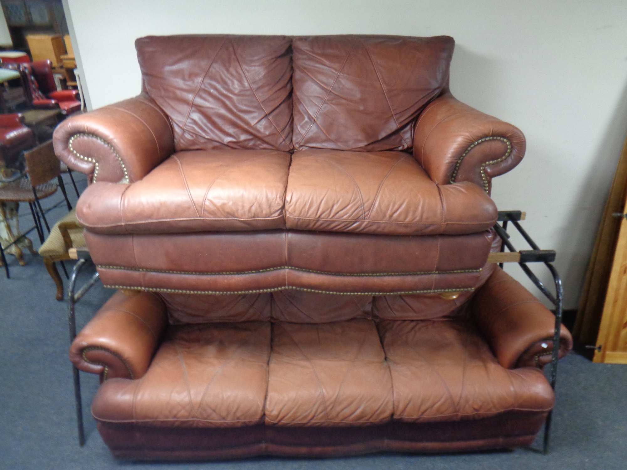 A brown leather scroll arm two seater and three seater settees