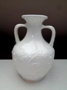 A 19th century Portland milk glass twin handled vase with embossed decoration, height 25.